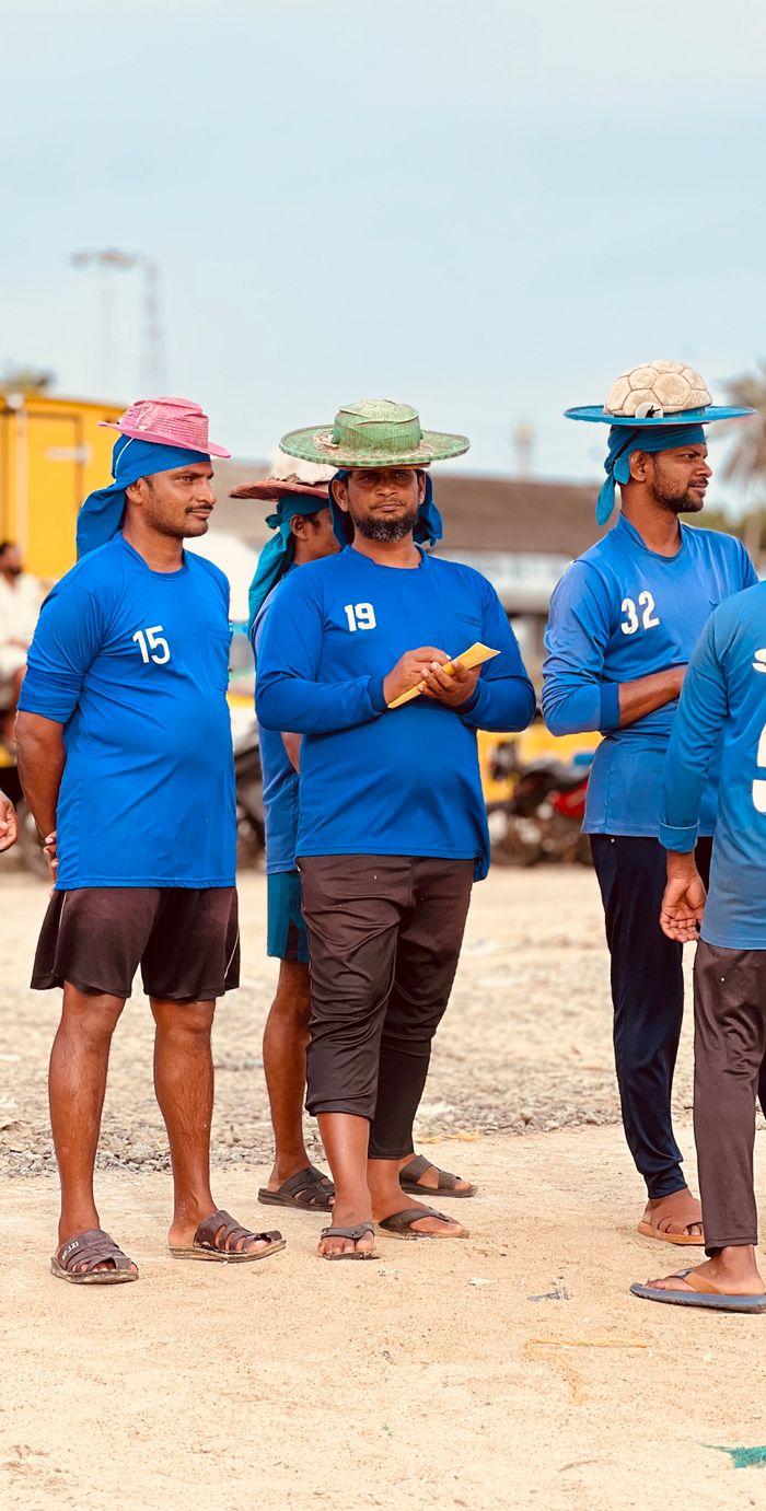 A group of adults wearing blue uniforms and hats standing outdoors in a casual setting.