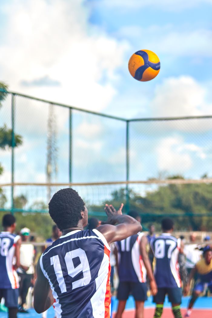 Athletes competing in a dynamic outdoor volleyball match on a sunny day.